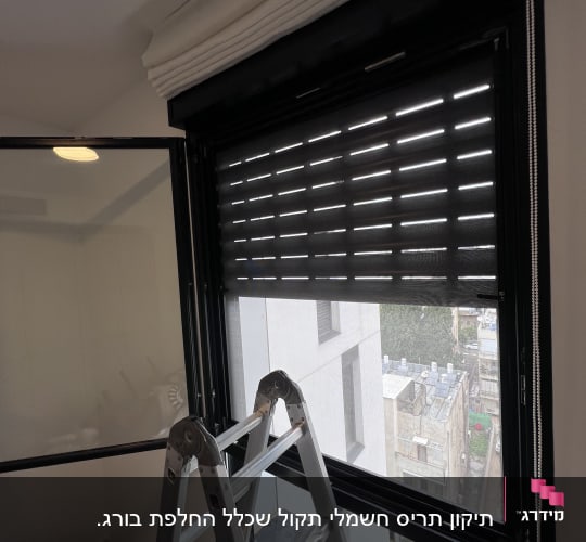 תריסים שחורים פתוחים חלקית עם סולם מתחת לחלון